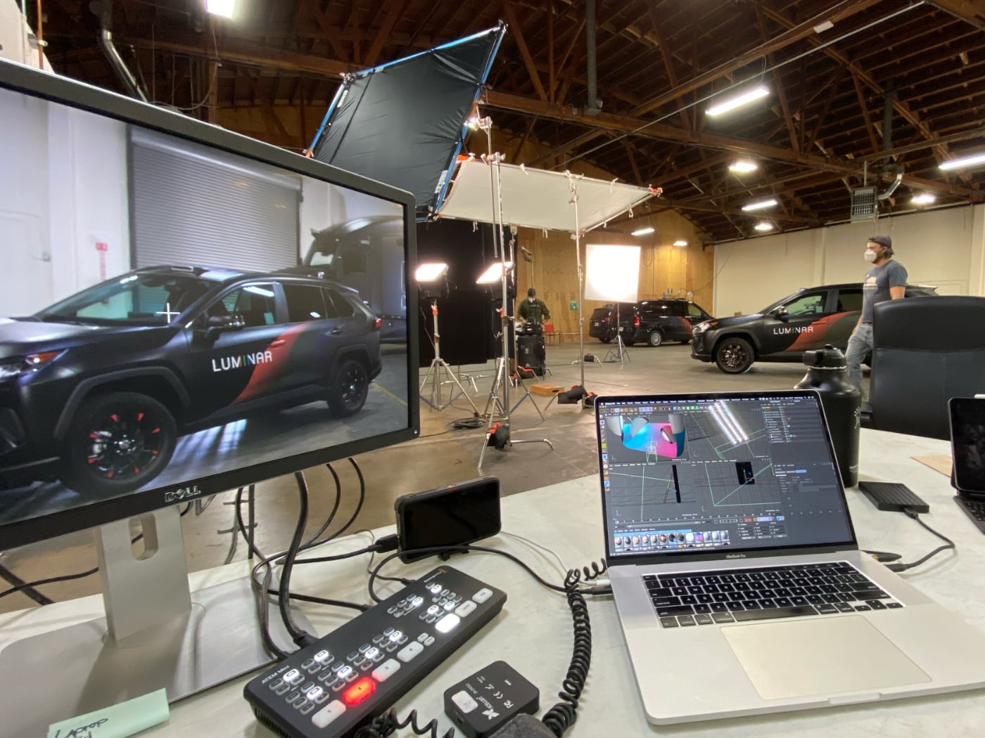 Behind the scenes of a Luminar video shoot with cars, lights, monitors, and a laptop